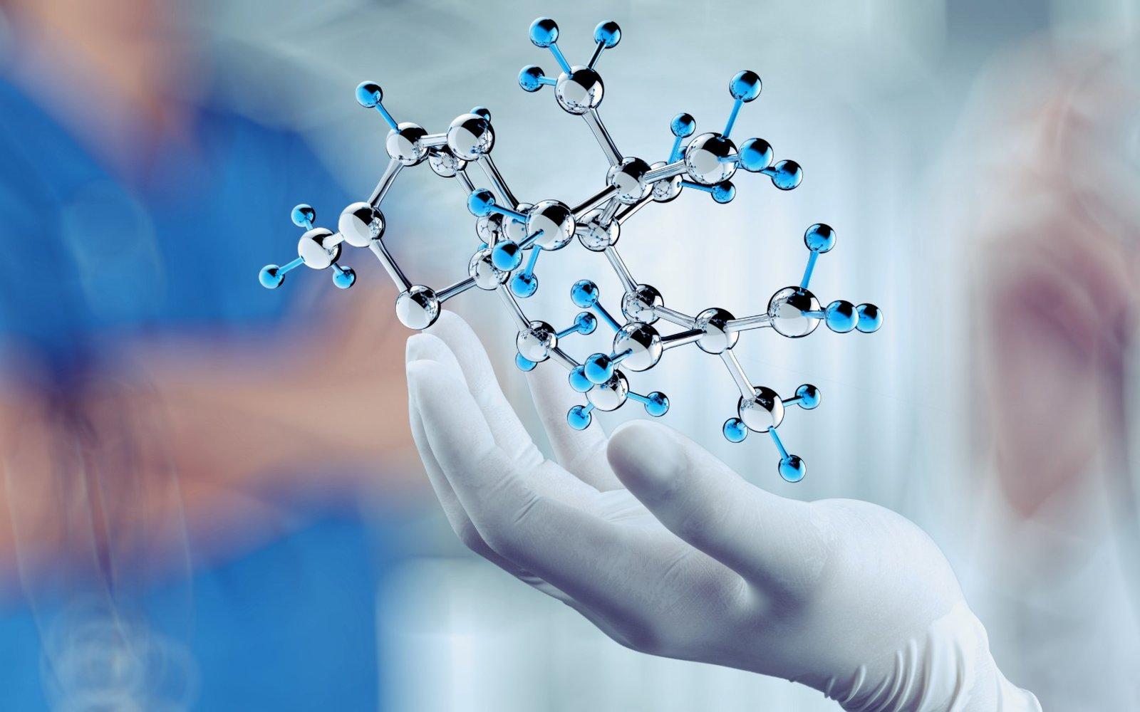 Gloved hand holding a glowing model of a molecule